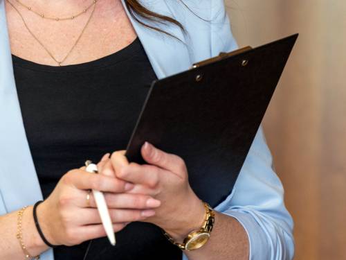 Eine Frau hält ein Klemmbrett und einen Kugelschreiber in ihren Händen