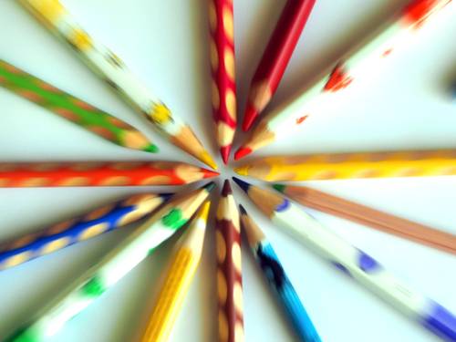 Buntstifte bilden einen Kreis, indem sie jeweils mit der Spitze zueinander zeigen. Ein dynamischer Effekt wird durch den Reisszoom erzeugt.