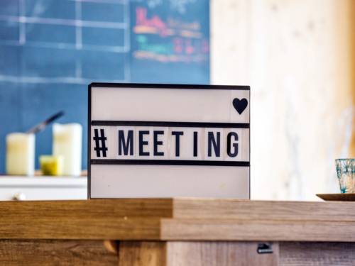Auf einem Tisch steht ein beleuchtbares Schild mit den Zeichen: "#MEETING".