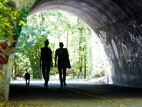 Zwei Menschen und ein Hund gehen durch einen Tunnel.