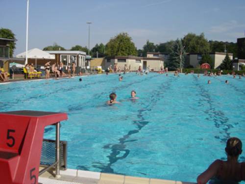 Ein gut gefülltes Schwimmerbecken unter freien Himmel.