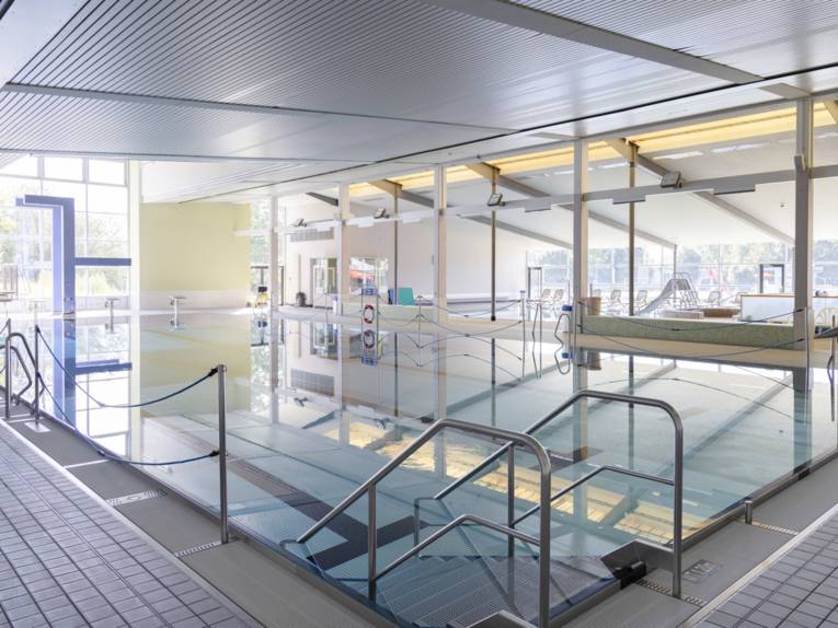 Hallenbad Schwimmbereich mit Startblöcken und Treppe ins Wasser