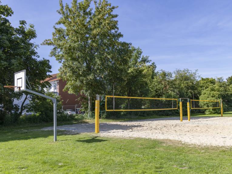 Grrünfläche mit Basektballkorb und Beachvolleyballfeld