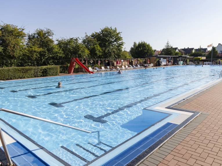 Schwimmbecken mit Badegästen und Rutsche
