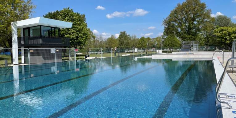 Eingezäuntes, mit Wasser gefülltes, menschenleeres Schwimmbecken, bei Sonnenschein