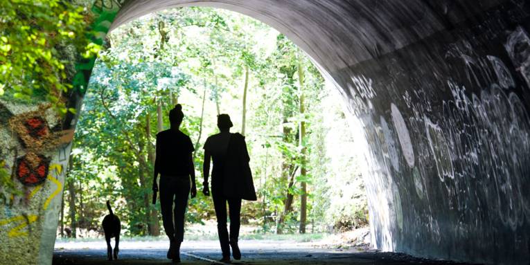 Zwei Menschen und ein Hund gehen durch einen Tunnel.