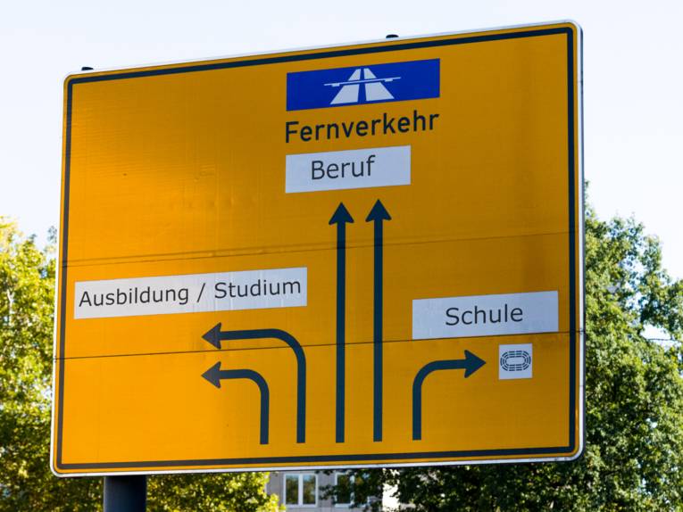 Ein Orientierungsschild zeigt an verschiedenen Pfeilen die Worte "Fernverkehr", "Beruf", "Ausbildung / Studium" und "Schule".