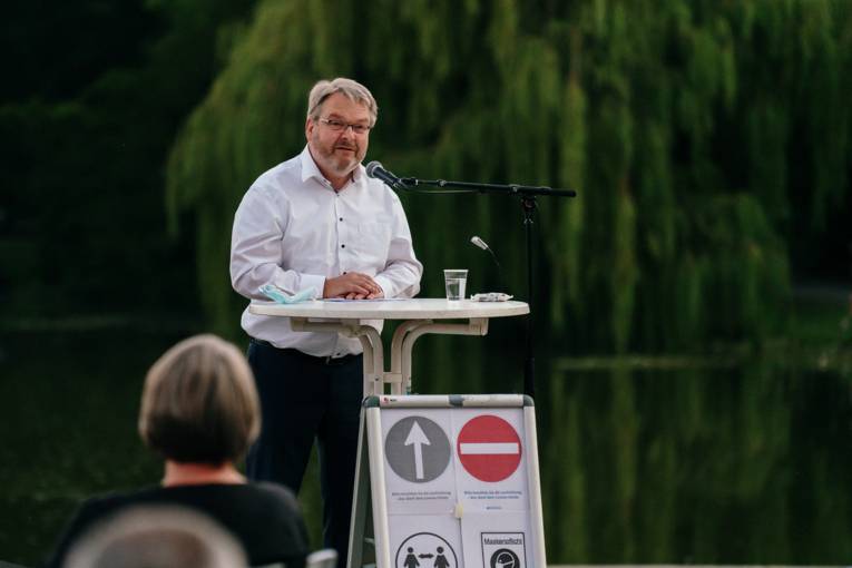 Bürgermeister Thomas Herrmann bei einer Rede, im Hintergrund der Maschpark.