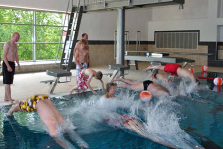 Schwimmer springen mit einem Kopfsprung vom Beckenrand